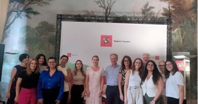 Group of people posing for a photo in front of a white backdrop with the Regione Toscana logo.