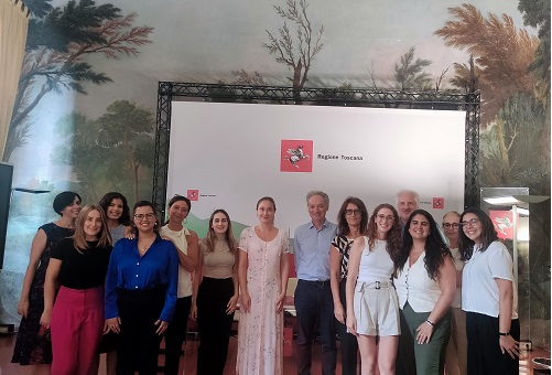Group of people posing for a photo in front of a white backdrop with the Regione Toscana logo.