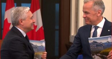 Two men in suits shake hands in a formal setting, with Canadian flags behind them, each holding a booklet featuring a mountain landscape.