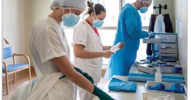 Team of healthcare workers in PPE prepping medical supplies at a clinic.