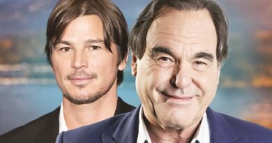 Two men posing for a portrait; younger man left with dark hair, older man right in a blue blazer, warm blurred background.