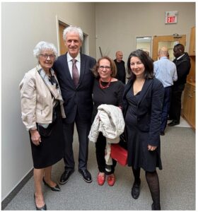 Four professionals posing for a photo in an office hallway, smiling at the camera.