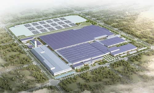 Aerial view of a large industrial campus with extensive blue solar panels on rooftops and a fenced perimeter around the site.