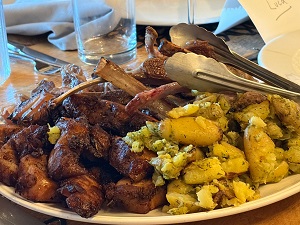 Plate with crispy roasted potatoes on the left and potato salad with peas on the right; tongs rest on the plate.