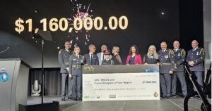 Uniformed officials on a stage presenting a giant ceremonial check for $1,160,000 to Crime Stoppers of York Region, with a large amount display in the background.