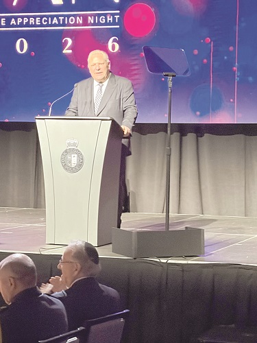 Man in a suit speaks at a lectern on a stage during Appreciation Night 2026 event.