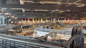 Large industrial production hall with steel beams, conveyor lines, and complex cabling.