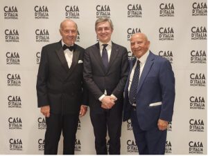 Three men in dark suits posing for a photo at Casa d'Italia Montreal, backdrop shows the event logo.