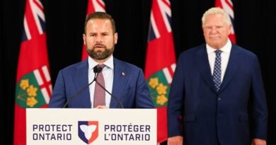 A man speaks at a podium labeled Protect Ontario / Protéger l’Ontario, with another suited man standing behind him, Ontario flags in the background.