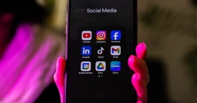 Hand holding a smartphone displaying a grid of social media app icons under the label 'Social Media'.