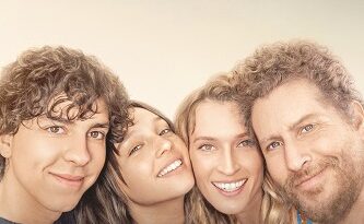 Group of four smiling friends posing together in front of a soft sunset gradient, promotional poster for 'Feel My Voice'.