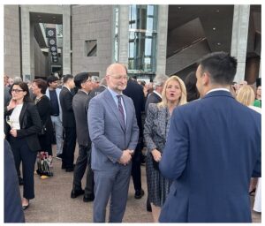 Group of professionals networking outside a modern office building at a business event, chatting in small groups.