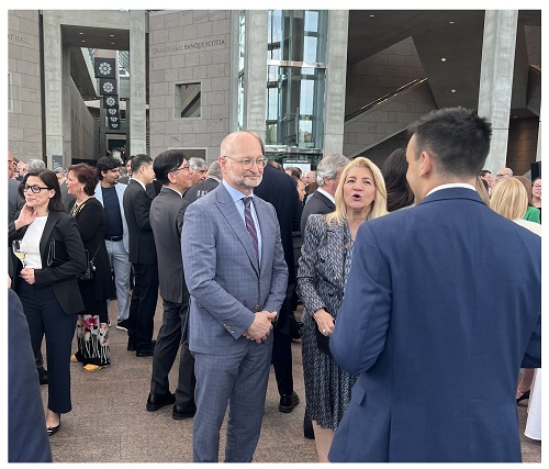 Group of professionals networking outside a modern office building at a business event, chatting in small groups.