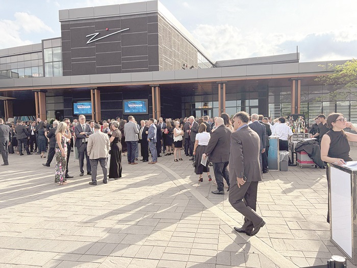Professionals in business attire mingle outside a modern office building during a corporate reception event.