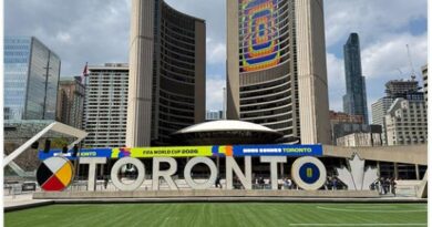 Toronto sign with large TO RONTO letters in front of tall buildings and a football field, celebrating FIFA World Cup 2026 in Toronto
