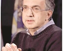 Middle-aged man with glasses wearing a dark sweater, speaking at a panel or event