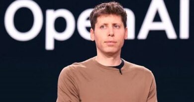 Man in a brown shirt standing on a stage with a large OpenAI logo in the background.